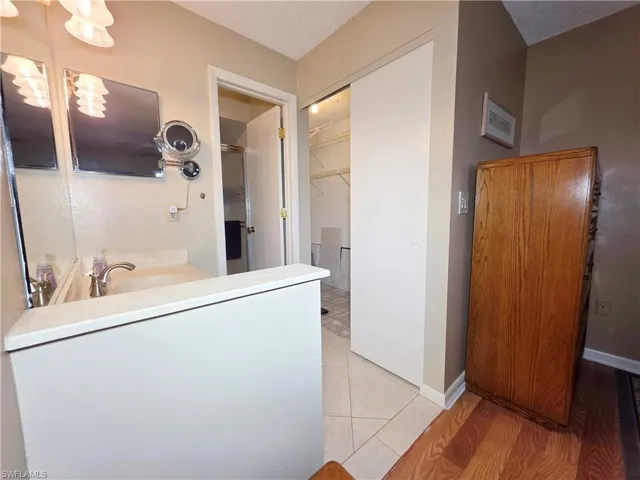 Full bath with a walk in closet, light tile patterned flooring, vanity, and a textured ceiling