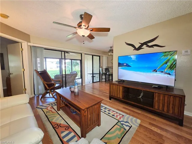 Living room with wood finished floors, a textured ceiling, and ceiling fan