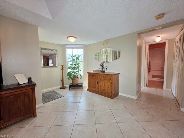 Hallway featuring a textured ceiling and light tile patterned floors