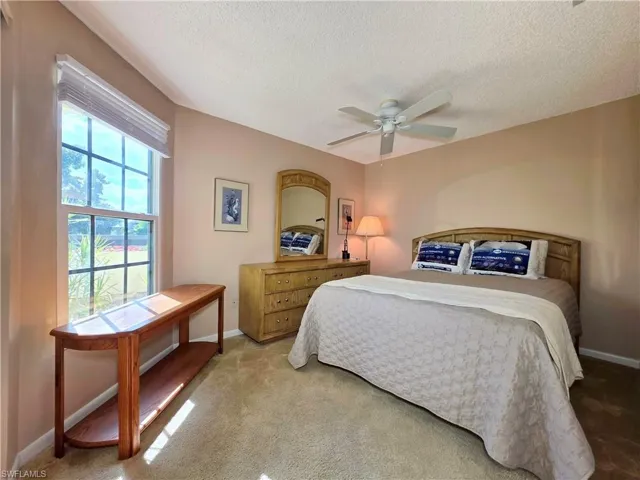 Bedroom with a textured ceiling, ceiling fan, and carpet flooring
