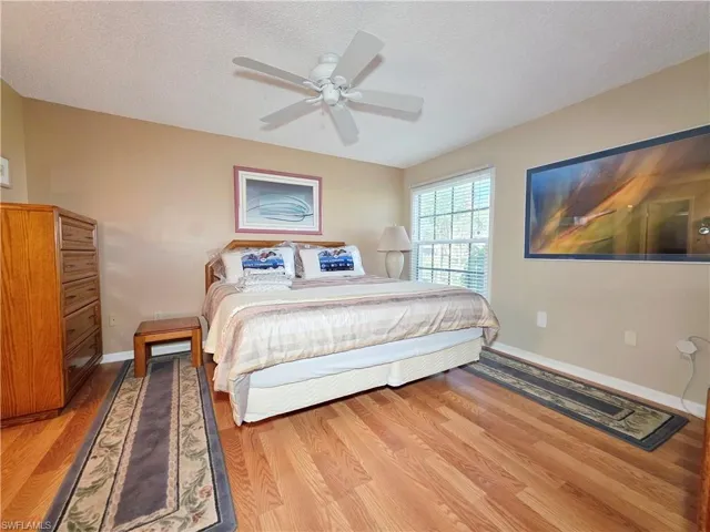 Bedroom featuring ceiling fan, wood finished floors, and a textured ceiling