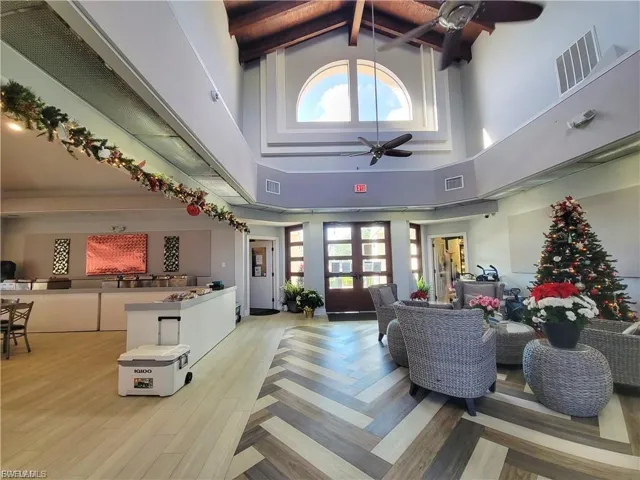 Living area with high vaulted ceiling, ceiling fan, light wood-style floors, and beamed ceiling