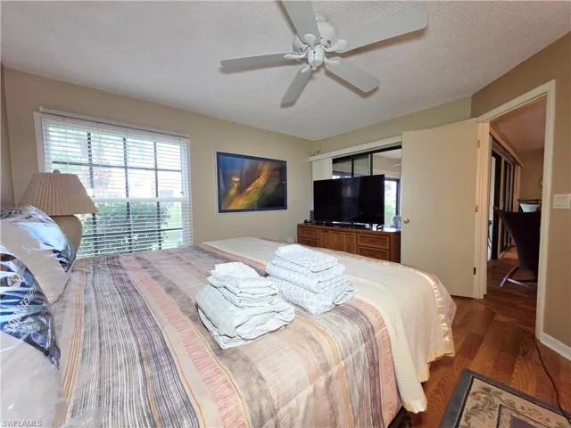 Bedroom with wood finished floors, a textured ceiling, and a ceiling fan