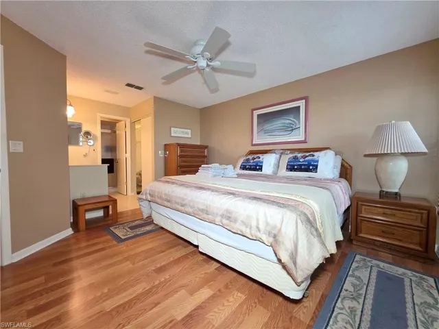 Bedroom with a closet, a ceiling fan, wood finished floors, and a textured ceiling