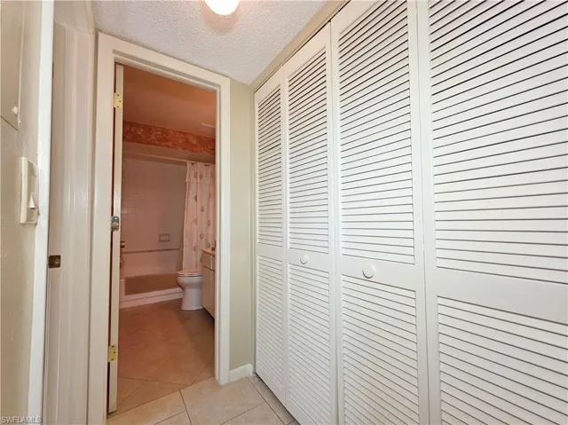 Corridor with light tile patterned floors and a textured ceiling
