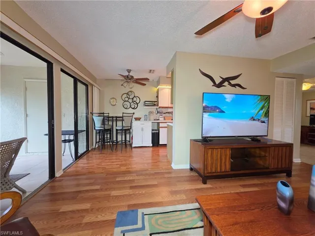 Living area featuring light wood-style floors, a textured ceiling, and a ceiling fan