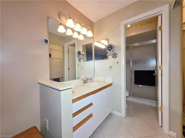 Bathroom with vanity, a spacious closet, a stall shower, and light tile patterned floors