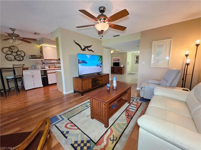Living room featuring a ceiling fan, light wood-style flooring, and a textured ceiling