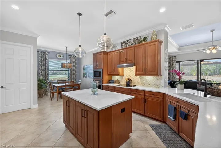 Kitchen with wood finish cabinets, hanging light fixtures, a kitchen island, plenty of natural light, and crown molding