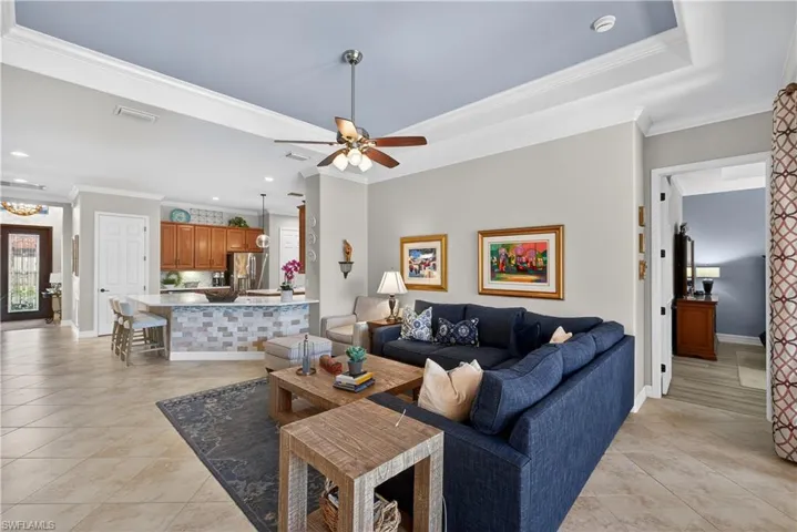 Living area with a ceiling fan, ornamental molding, light tile patterned floors, and recessed lighting