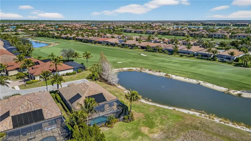 Aerial view of residential area featuring a nearby body of water and a golf course