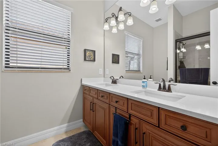 Full bathroom with double vanity, a stall shower, and light tile patterned flooring