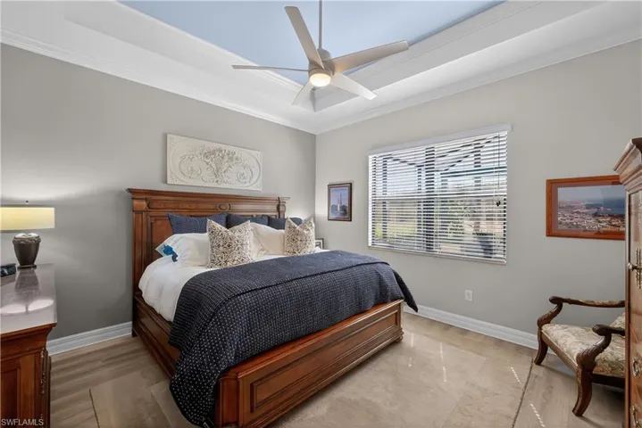 Bedroom featuring ornamental molding, a tray ceiling, a ceiling fan, and wood finished floors