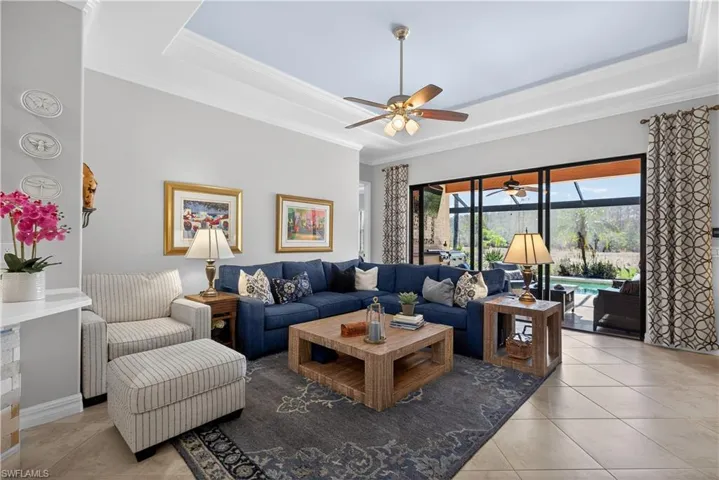 Living area featuring a tray ceiling, crown molding, a ceiling fan, and light tile patterned floors
