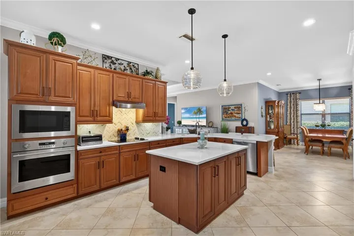 Kitchen featuring wood finish cabinets, a peninsula, stainless steel appliances, decorative light fixtures, and a center island