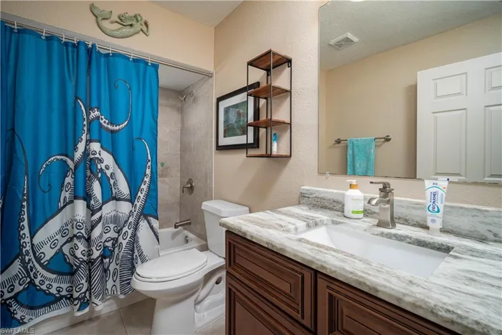 Full bathroom featuring toilet, vanity, shower / bath combo, tile patterned floors, and a textured ceiling
