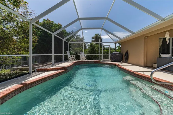 View of pool with glass enclosure and a patio area