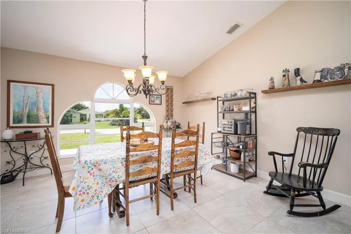 Dining space featuring a notable chandelier, high vaulted ceiling, and light tile patterned floors