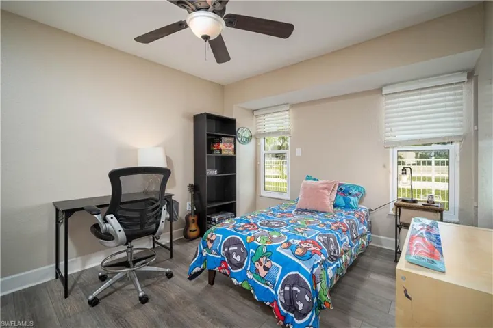 Bedroom with ceiling fan, dark hardwood / wood-style flooring, and multiple windows