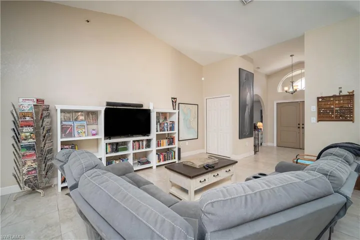 Living room with high vaulted ceiling, an inviting chandelier, and light tile patterned flooring