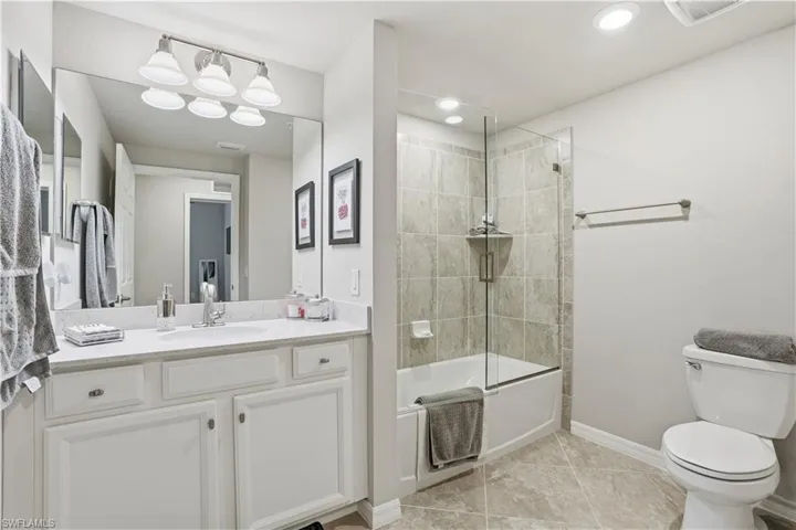 Full bathroom with vanity, enclosed tub / shower combo, and light tile patterned floors