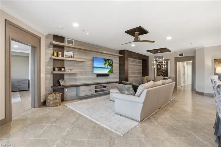 Living room featuring ornamental molding, a ceiling fan, an accent wall, recessed lighting, and light tile patterned flooring