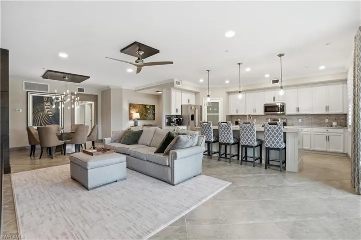 Living room with crown molding, a ceiling fan, and hanging lights