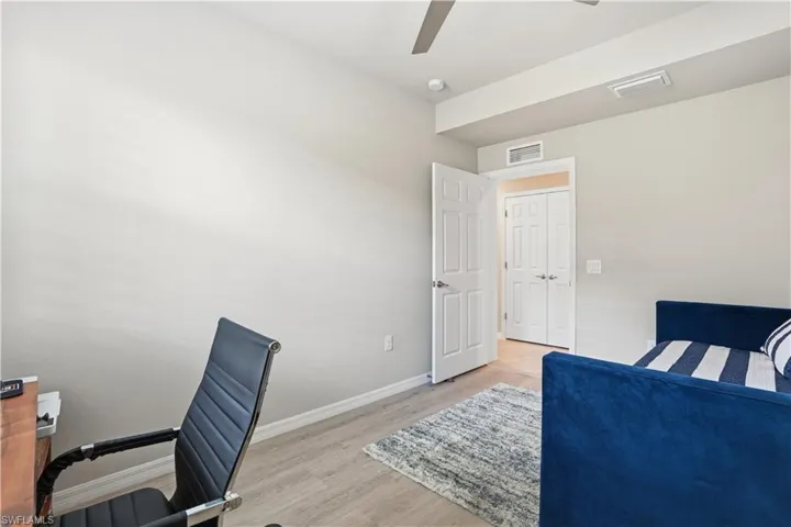 Bedroom with a desk, light wood-style flooring, and ceiling fan