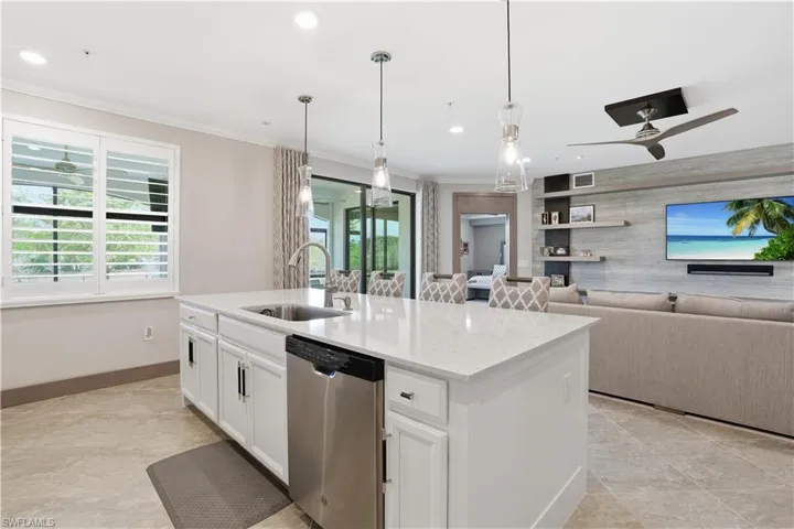 Kitchen featuring dishwasher, white cabinetry, a ceiling fan, an island with sink, and light stone countertops