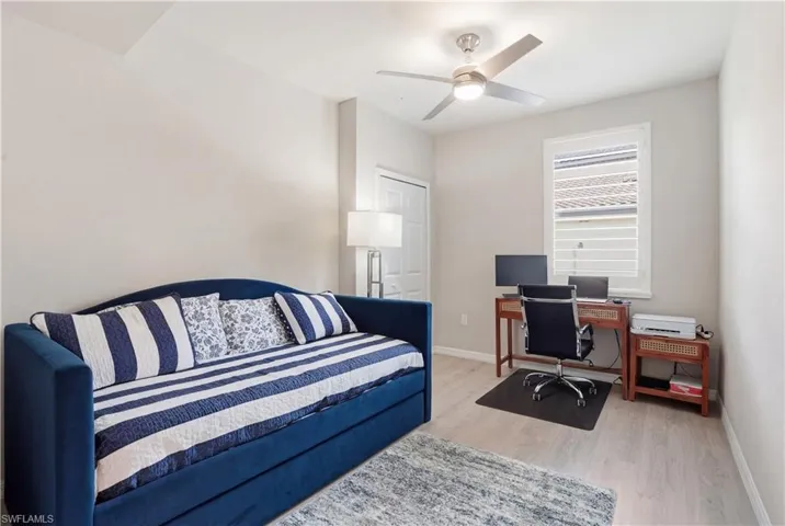 Bedroom featuring light wood-style floors, an office area, and ceiling fan