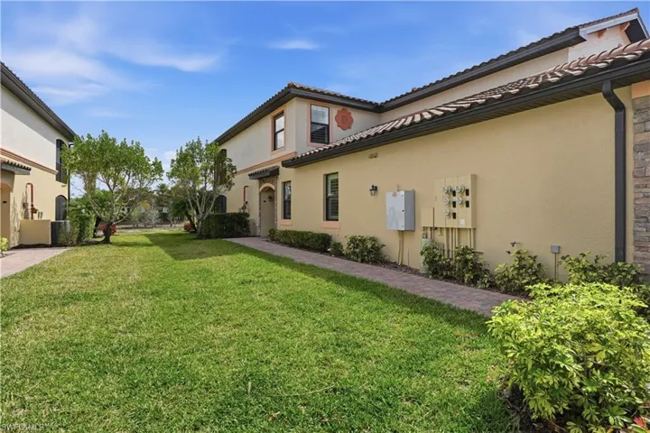 View of side of home featuring stucco siding, a lawn, and a tiled roof