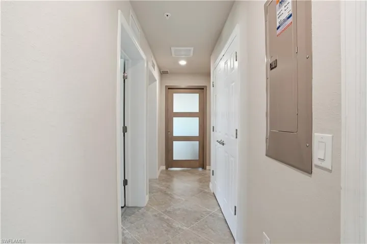 Hallway featuring electric panel, a textured wall, and recessed lighting