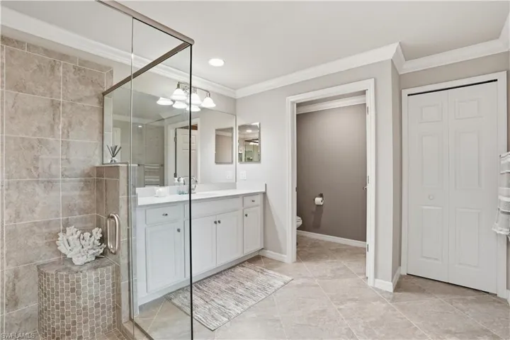 Full bath with a closet, ornamental molding, vanity, a shower stall, and recessed lighting