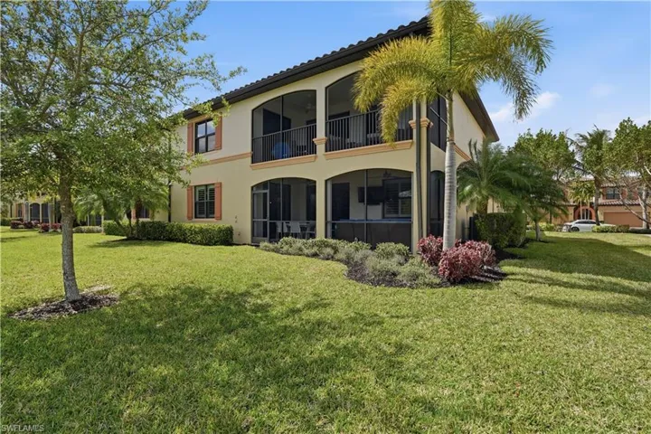 Back of house featuring a sunroom, a balcony, a lawn, and stucco siding