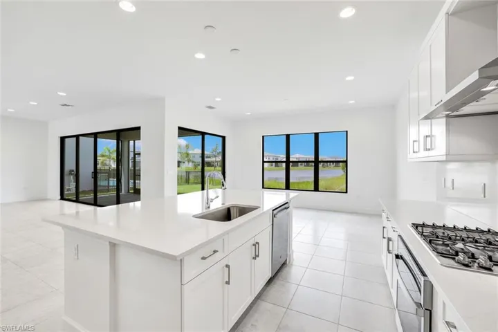 Kitchen with stainless steel appliances, sink, an island with sink, wall chimney exhaust hood, and white cabinets