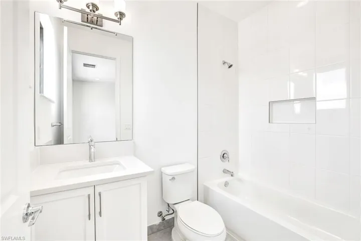 Full bathroom featuring tiled shower / bath combo, vanity, and toilet