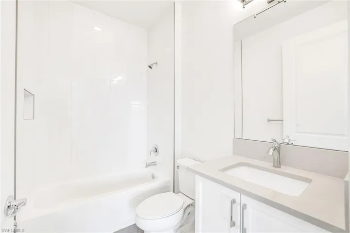 Full bathroom featuring tiled shower / bath, vanity, and toilet
