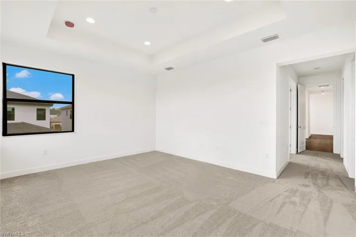 Empty room featuring light colored carpet and a tray ceiling