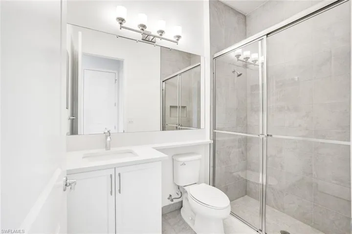 Bathroom with tile patterned flooring, walk in shower, toilet, and vanity