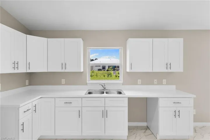 Kitchen with light marble finish flooring, white cabinets, and light countertops