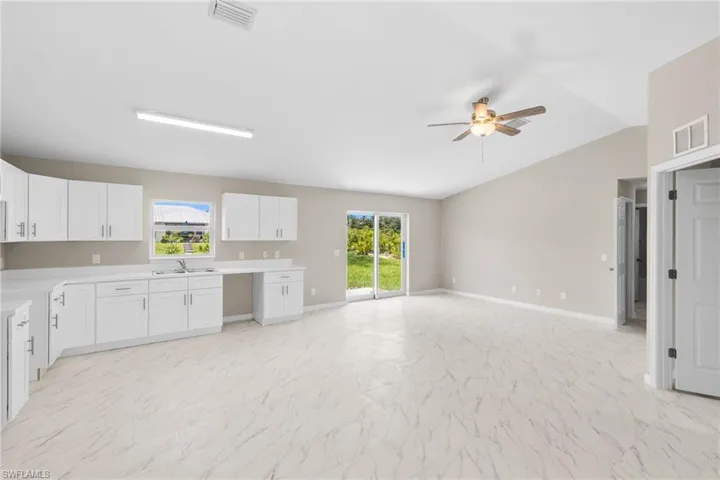 Kitchen featuring a ceiling fan, white cabinets, vaulted ceiling, light countertops, and open floor plan