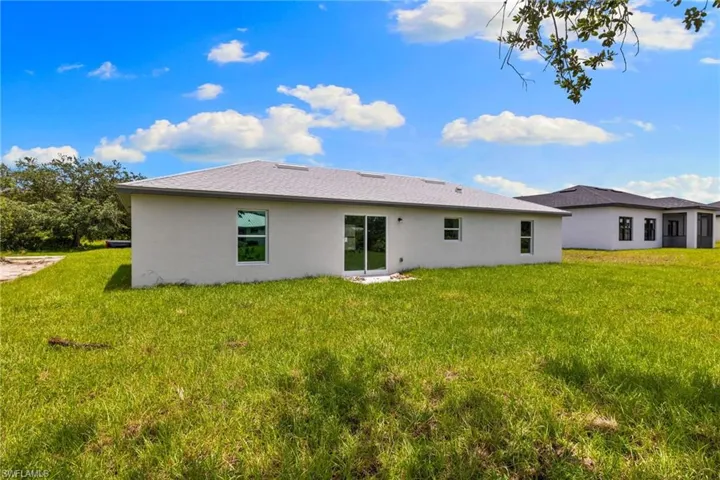 Rear view of house featuring stucco siding and a lawn