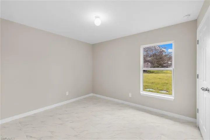 Spare room featuring light marble finish floors and baseboards