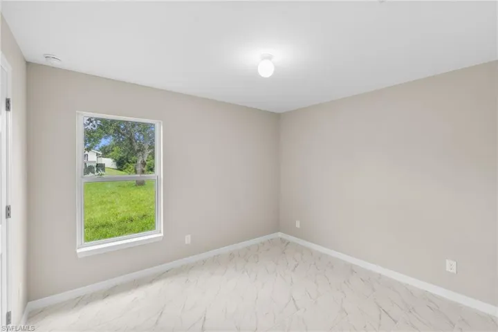 Unfurnished room with light marble finish flooring and healthy amount of natural light