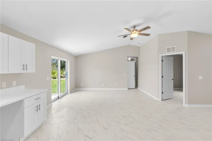 Unfurnished living room featuring ceiling fan, lofted ceiling, and light marble finish flooring