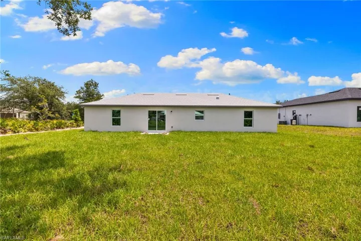 Back of house with a lawn and stucco siding
