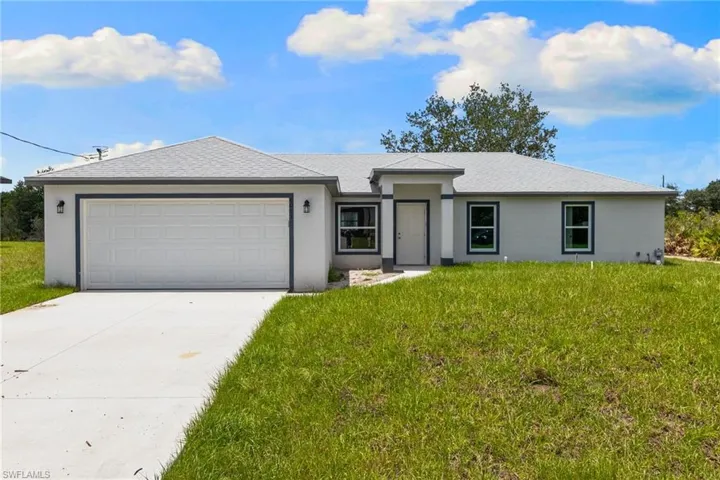 View of front of house featuring stucco siding, driveway, and a garage