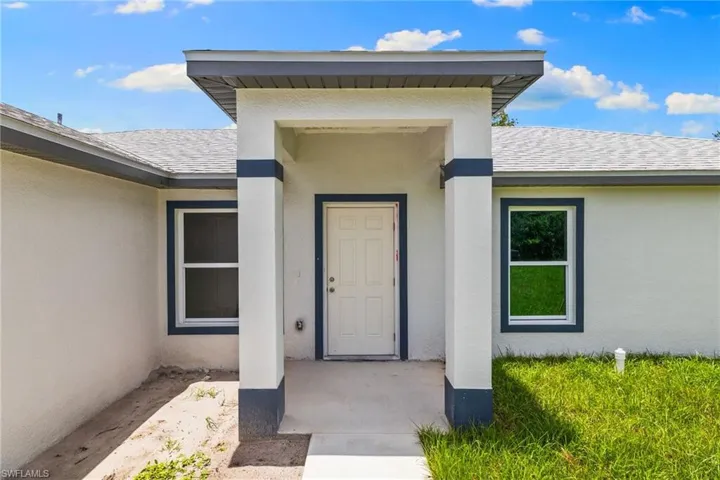 Doorway to property featuring stucco siding and a shingled roof