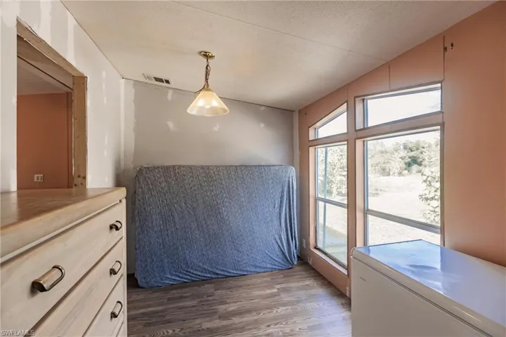 Bedroom featuring dark hardwood / wood-style floors, lofted ceiling, and a textured ceiling