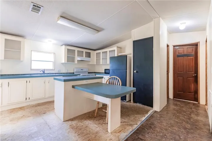 Kitchen featuring white cabinets, fridge, white range oven, a kitchen island, and a breakfast bar